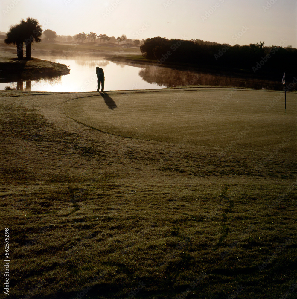 Man contemplates stroke on golf course at dawn. Man contemplates stroke on golf course at dawn.