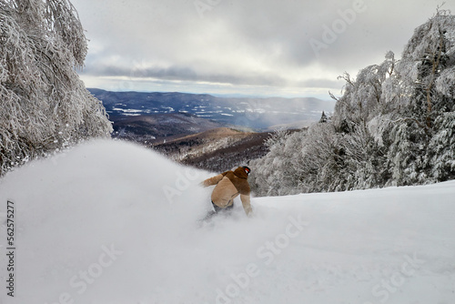 Snowboarder riding down hill in snow photo
