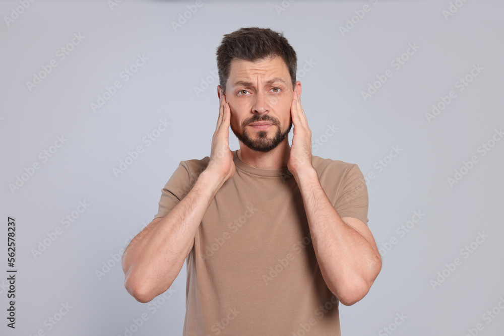 Man suffering from ear pain on grey background Man suffering from ear pain on grey background
