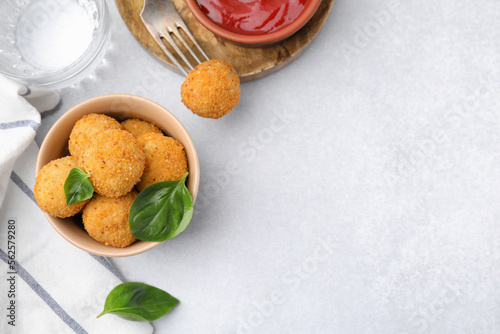 Bowl of delicious fried tofu balls with basil and ketchup on white table, flat lay. Space for text