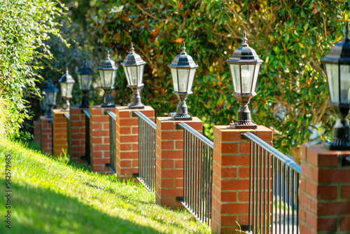 Fotografia Row of decorative black metal lanterns on brick square wall posts with rod iron
