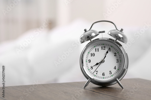 Silver alarm clock on wooden table indoors. Space for text