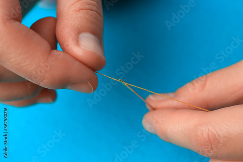Closeup view of woman threading sewing needle