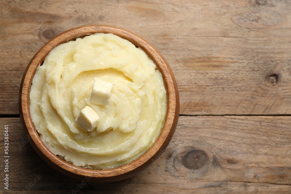 Bowl of delicious mashed potato with butter on wooden table, top view. Space for text Bowl of delicious mashed potato with butter on wooden table, top view. Space for text