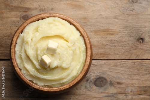 Bowl of delicious mashed potato with butter on wooden table, top view. Space for text