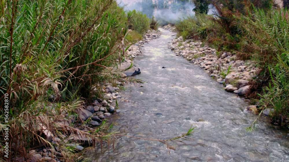 Pathway Of Water Flowing In River Sided With Stones And Green Grass Pathway Of Water Flowing In River Sided With Stones And Green Grass