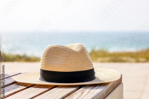 Fototapeta Naklejka Na Ścianę i Meble -  Summer hat on bench at sea resort, closeup
