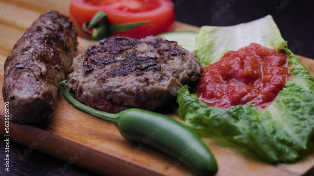 Adjusting cucumber slices on a plate with traditional Bulgarian barbecue dish of kyufte, kebapche and lyutenica. Adjusting cucumber slices on a plate with traditional Bulgarian barbecue dish of kyufte, kebapche and lyutenica.