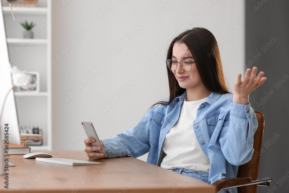Young woman using mobile phone at table in office Young woman using mobile phone at table in office