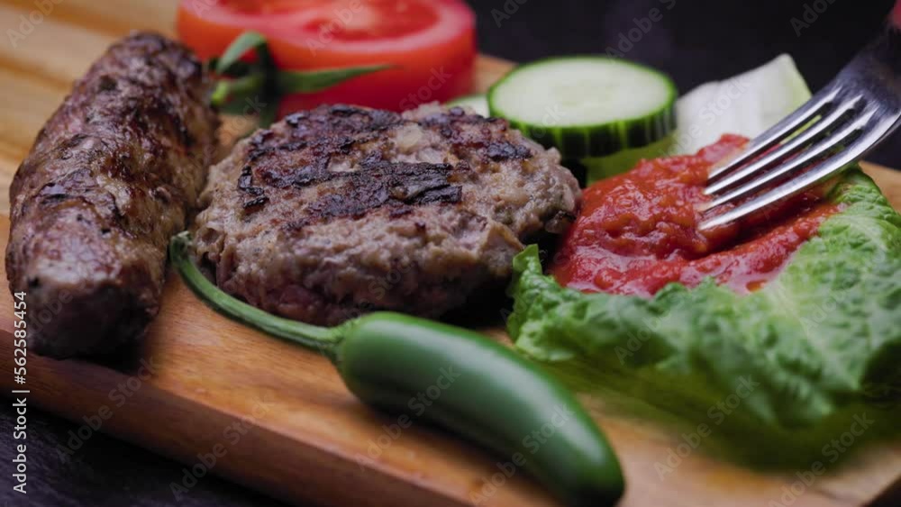 Traditional Bulgarian tomato and roasted pepper spread known as lyutenica mixed with a fork and served as a garnish for a barbecue dish. Traditional Bulgarian tomato and roasted pepper spread known as lyutenica mixed with a fork and served as a garnish for a barbecue dish.