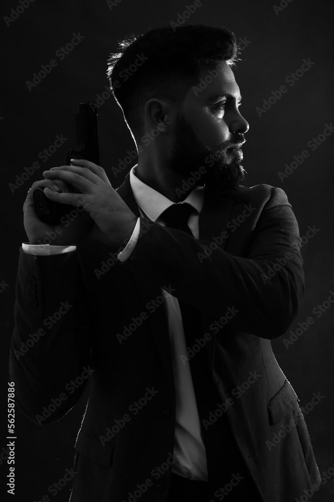 Silhouette of young man in suit with gun on dark background Silhouette of young man in suit with gun on dark background