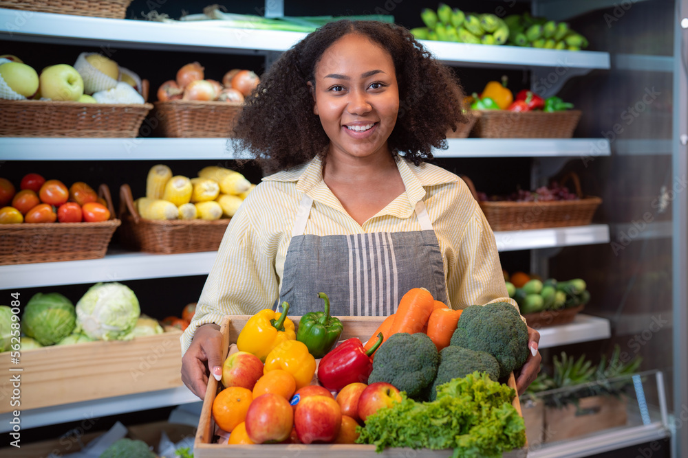 African american woman grocery working in supermarket with fruit and vegetable background