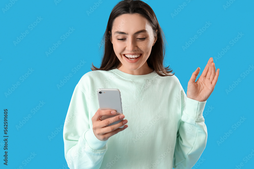 Young woman using mobile phone on blue background Young woman using mobile phone on blue background