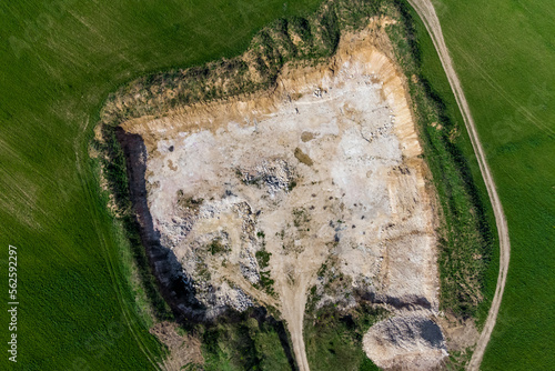 View from a high altitude of a stone quarry dug in the middle of a green field, limestone open pit mining