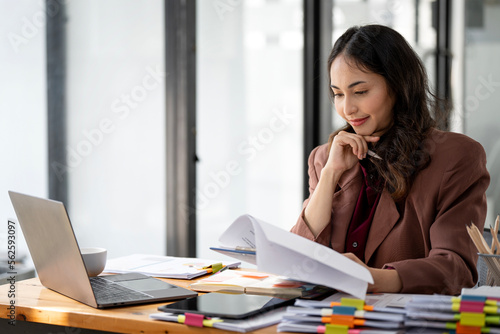 Asian indian businesswoman working on laptop computer and document in open office.