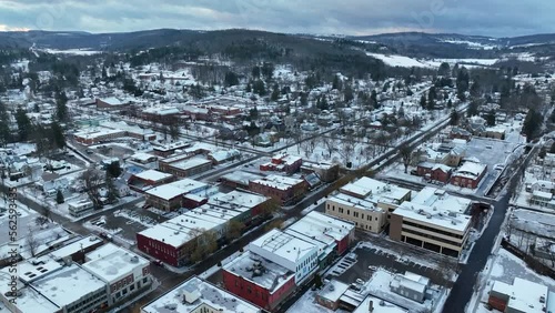 High aerial pull back of sprawling snow covered town in America. Wellsboro PA drone view on December, Christmas, winter day. photo