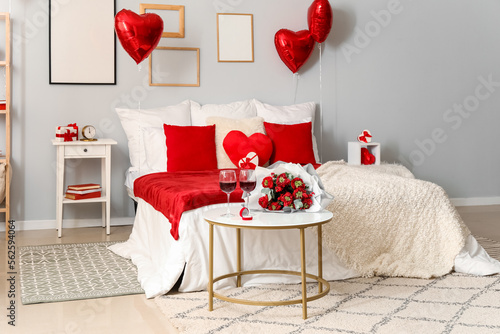 Interior of bedroom decorated for Valentine's Day with flowers, wine glasses and engagement ring