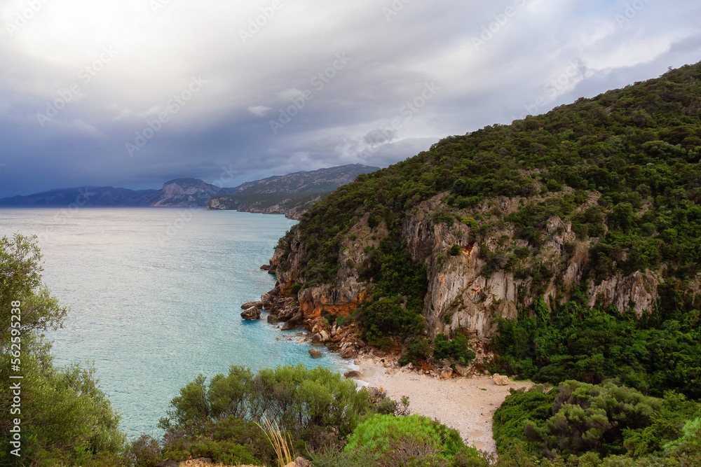 Sandy Beach on a rocky coast near Cala Gonone, Sardinia. Cloudy Sunrise Sky.