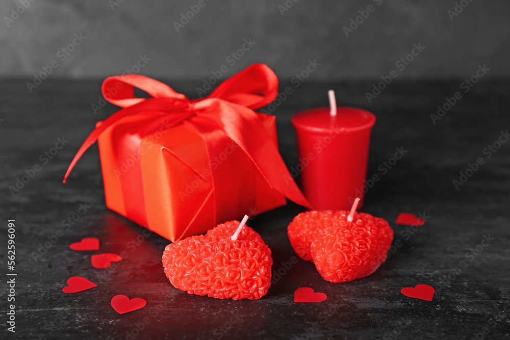 Beautiful candles, gift box and paper decor on dark background. Valentine's Day celebration Beautiful candles, gift box and paper decor on dark background. Valentine's Day celebration