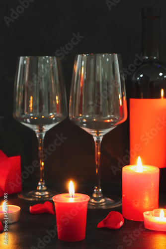 Burning candles, glasses and bottle of wine on dark background. Valentine's Day celebration