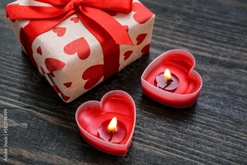 Fototapeta Naklejka Na Ścianę i Meble -  Burning candles and gift box on wooden background, closeup. Valentine's Day celebration