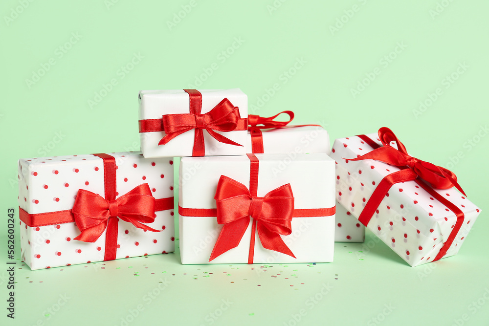 Obraz premium Gift boxes with beautiful bows on green background. Valentine's Day celebration