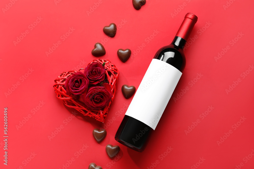 Bottle of wine, chocolate candies and rose flowers on red background. Valentine's Day celebration Bottle of wine, chocolate candies and rose flowers on red background. Valentine's Day celebration