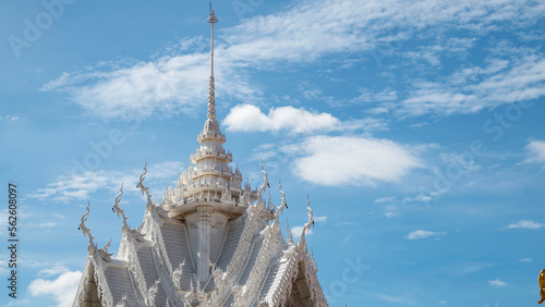 The roof of the Thai Buddhist temple against the background of the sky with clouds