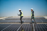 Well-equipped worker in protective clothing working and examining solar panels on a photovoltaic rooftop plant. Concept of maintenance and installation of solar station.