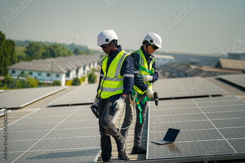 Well-equipped worker in protective clothing working and examining solar panels on a photovoltaic rooftop plant. Concept of maintenance and installation of solar station.