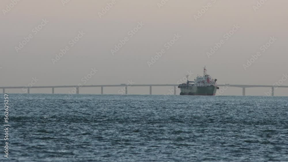 An old industrial vessel sails down a river against the backdrop of a bridge An old industrial vessel sails down a river against the backdrop of a bridge