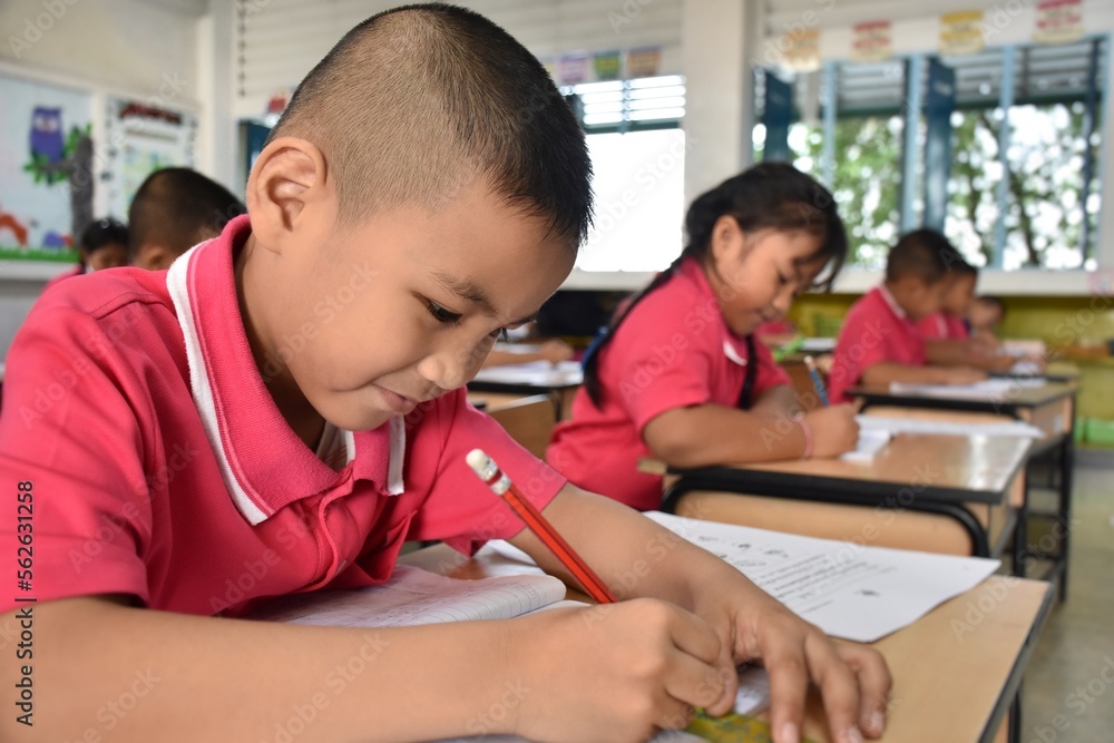 Early elementary school children in Thai student uniform are intending to make work sheets in the classroom. Early elementary school children in Thai student uniform are intending to make work sheets in the classroom.