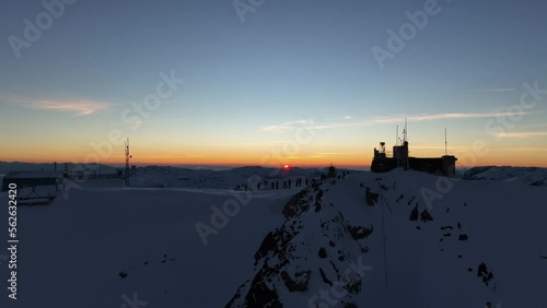 Drone shot passing through Musala peak, summit (2925m) during sunset, dusk, Bulgaria, Rila mountain, highest summit on the Balkans, clear sky, amazing, stunning view, twilight, blue hour, golden hour photo