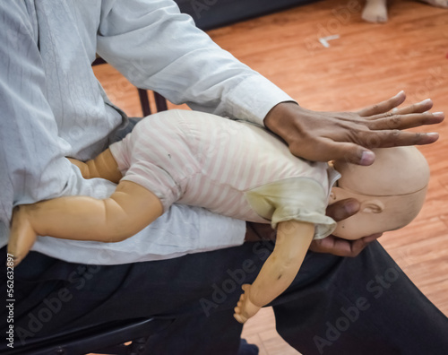 Man performing CPR on baby training doll dummy with one hand compression. First Aid Training - Cardiopulmonary resuscitation. First aid course on CPR dummy, CPR First Aid Training Concept