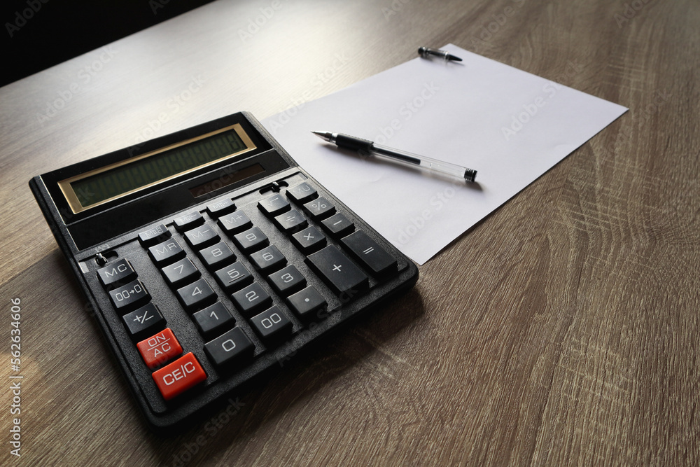 Calculator and pencil and white paper on a wooden desk. Calculation concept selective focus Calculator and pencil and white paper on a wooden desk. Calculation concept selective focus