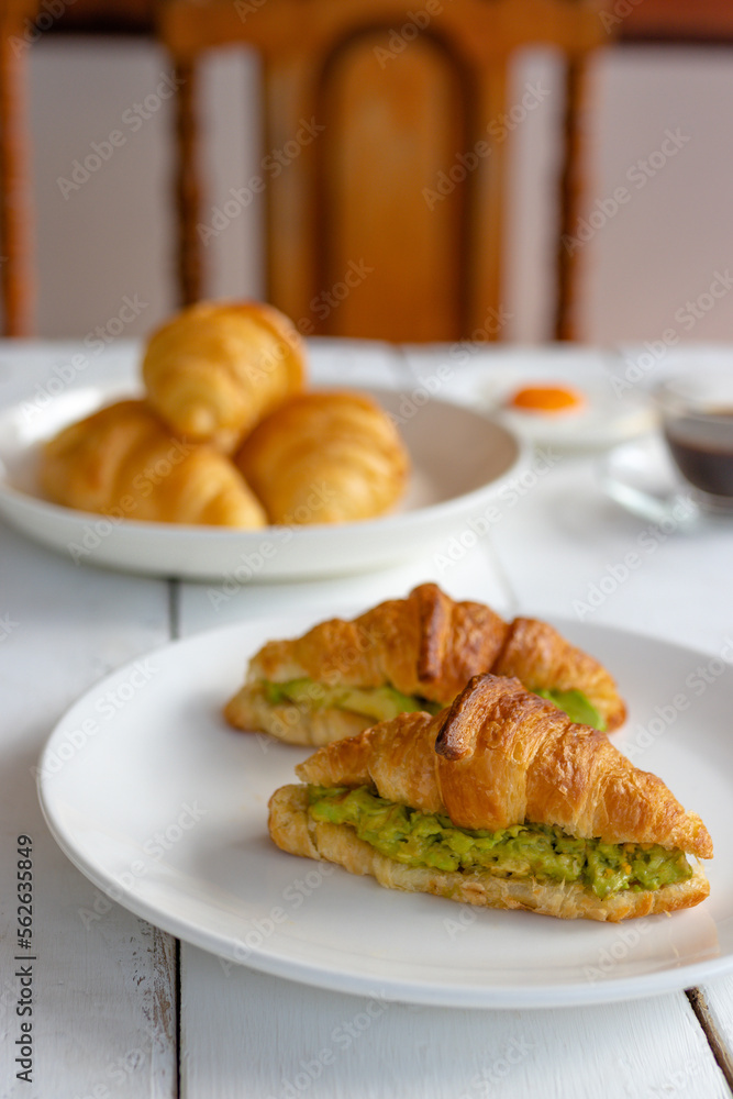 Croissant sandwich with egg,avocado on white dish and honey, coffee. breakfast and healthy food concept. Croissant sandwich with egg,avocado on white dish and honey, coffee. breakfast and healthy food concept.