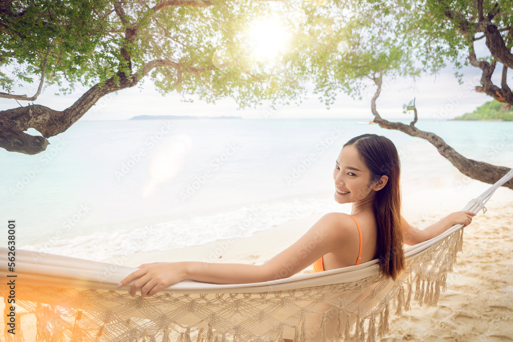 Asian woman traveller sleep on the swing cragle with bikini on the beach at Pataya Beach, Thailand