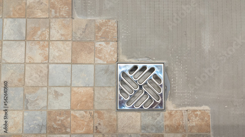 installation of new tiles on floor of Italian shower with evacuation of water diy tiling  work in progress in domestic bathroom photo