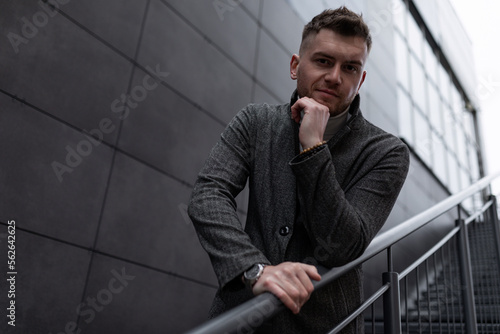 stylish business brutal man stands on the steps on the stairs