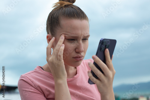 Girl with vision problems tries to read text on the phone. Bad vision concept. Woman looking at the screen of a mobile phone, having vision problems. selective focus