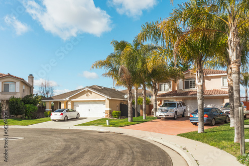 Beautiful houses with nicely landscaped front the yard, and cars parked on a sidewalk in small town in California.
