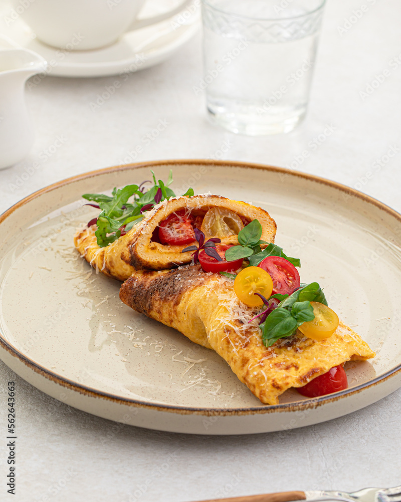 Portion of gourmet omelette with tomatoes, basil and parmesan Portion of gourmet omelette with tomatoes, basil and parmesan