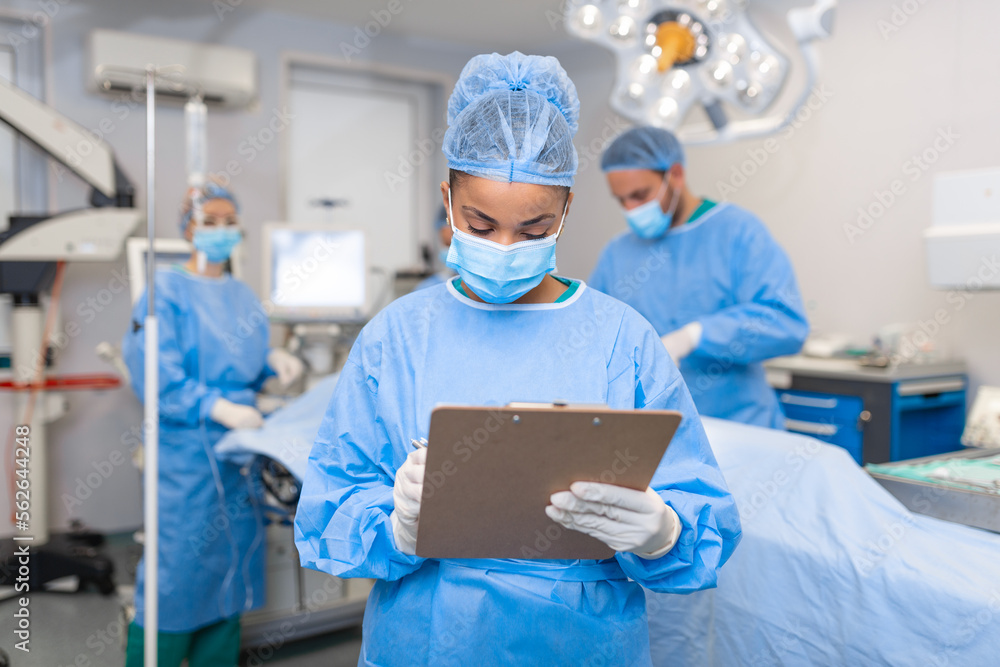 Surgeon writing on clipboard in operation room, anaesthesiologist writing the updates Surgeon writing on clipboard in operation room, anaesthesiologist writing the updates