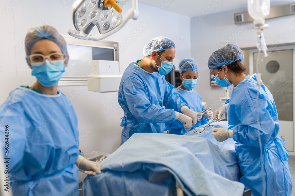 Group of medical team urgently doing surgical operation and helping patient in theater at hospital. Medical team performing surgical operation in a bright modern operating room Group of medical team urgently doing surgical operation and helping patient in theater at hospital. Medical team performing surgical operation in a bright modern operating room