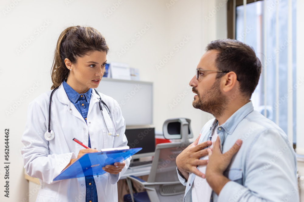 Fototapeta premium Experienced doctor discussing with patient his private medical file. Young man checking up with his MD, and consulting about the way of his health treatment and health insurance.