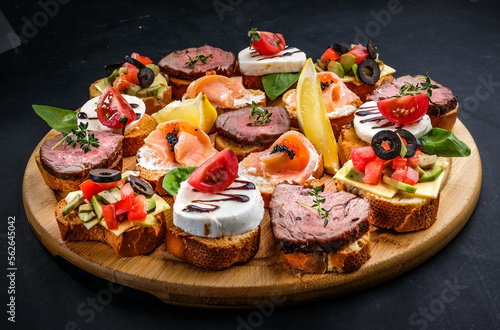 bruschetta with meat, cheese, salmon, lemon, tomato, olive