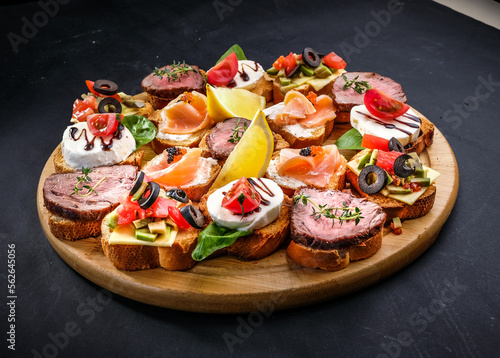 bruschetta with meat, cheese, salmon, lemon, tomato, olive