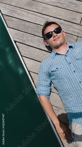 A guy in a blue shirt lies on the pier and smiles