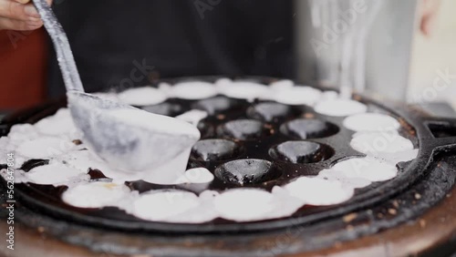 coconut rice pancake, kind of Thai sweetmeat, made from glutinous rice flour, sugar and coconut milk, poured in a container that look like small holes and set on the fire stove