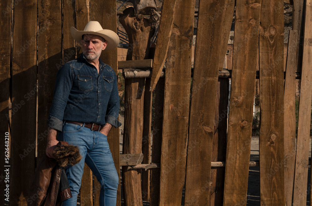Portrait of adult man in cowboy hat against wooden wall Portrait of adult man in cowboy hat against wooden wall